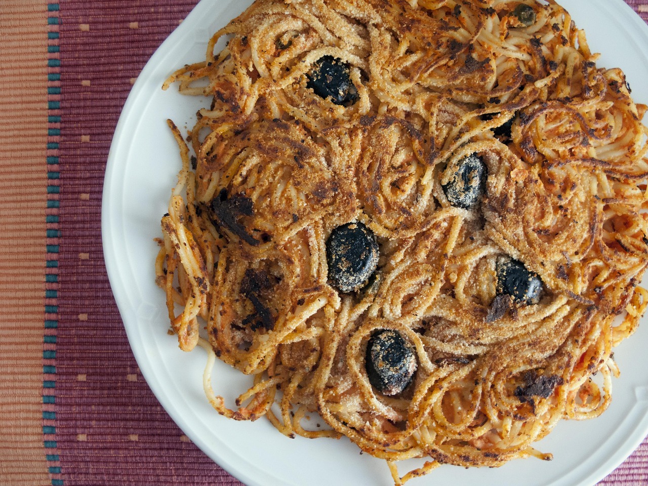 Pasta al forno croccante con pane grattugiato e fiocchetti di burro dorati.