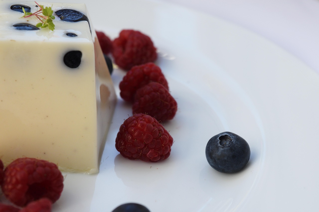 Panna cotta perfetta con consistenza morbida e tremolante, decorata con frutti di bosco freschi.